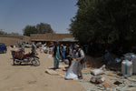 Men carry sack of almonds to sell at an outdoor market in Afghanistan